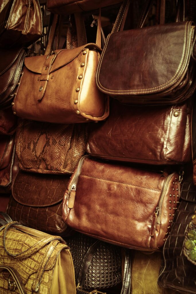 A collection of vintage leather bags in various styles and colors showcased in a market stall.